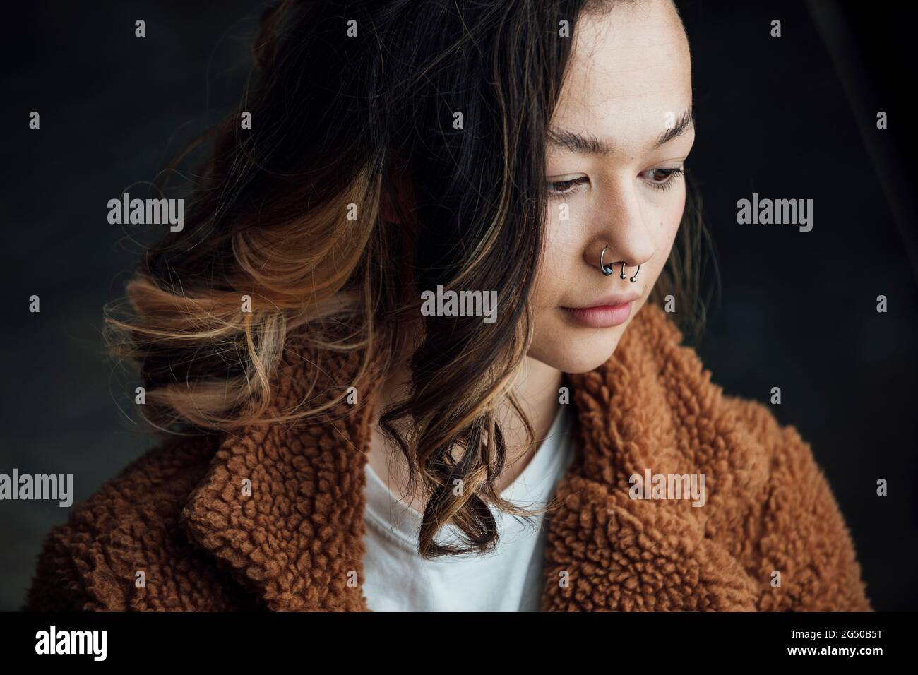 Una giovane donna contenta e alla moda che guarda lontano dalla fotocamera. Foto Stock
