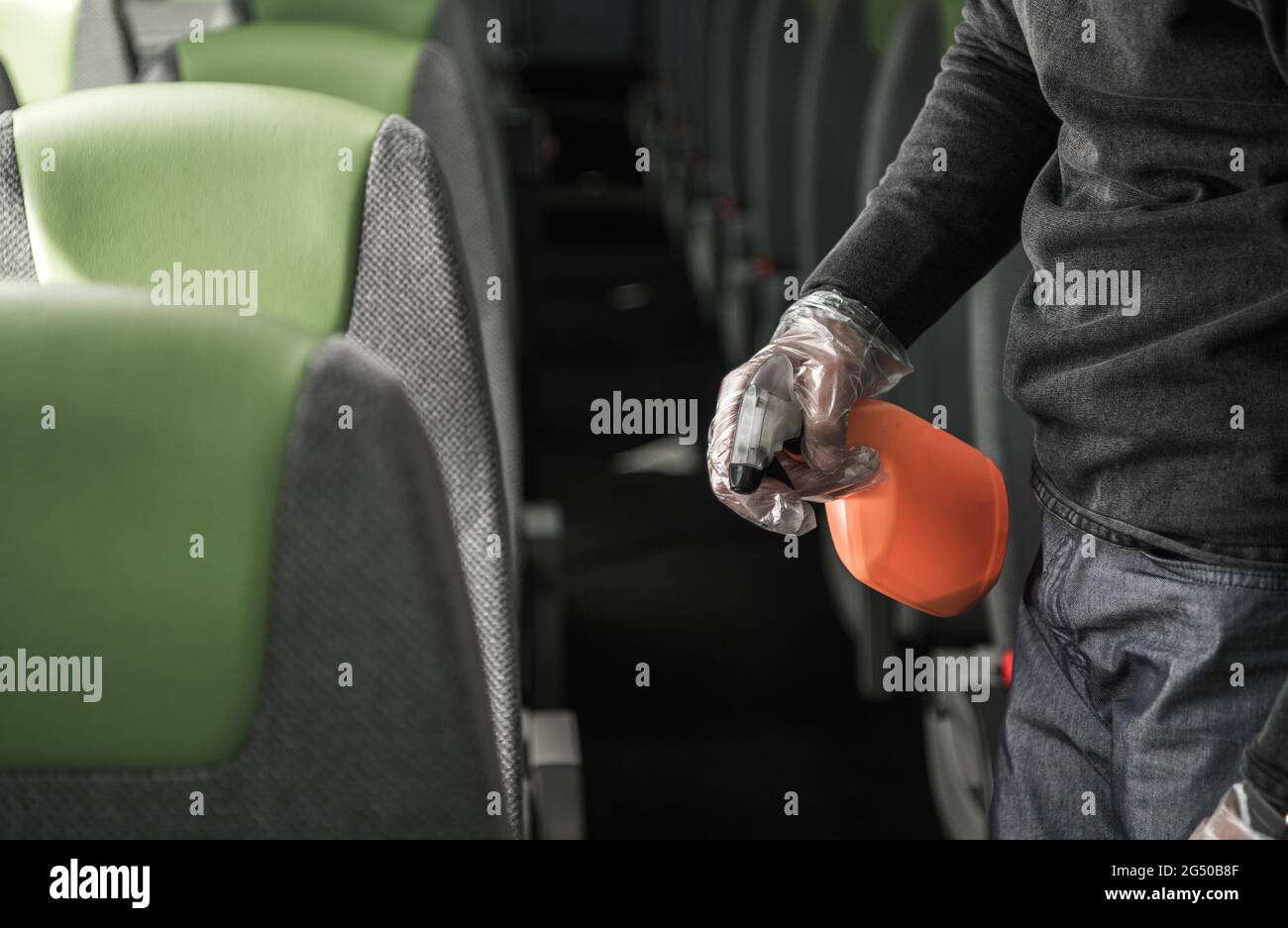 Pulendo e disinfettando i braccioli dei sedili del veicolo indossando guanti in vinile. Trasporti pubblici e tema pandemico. Foto Stock
