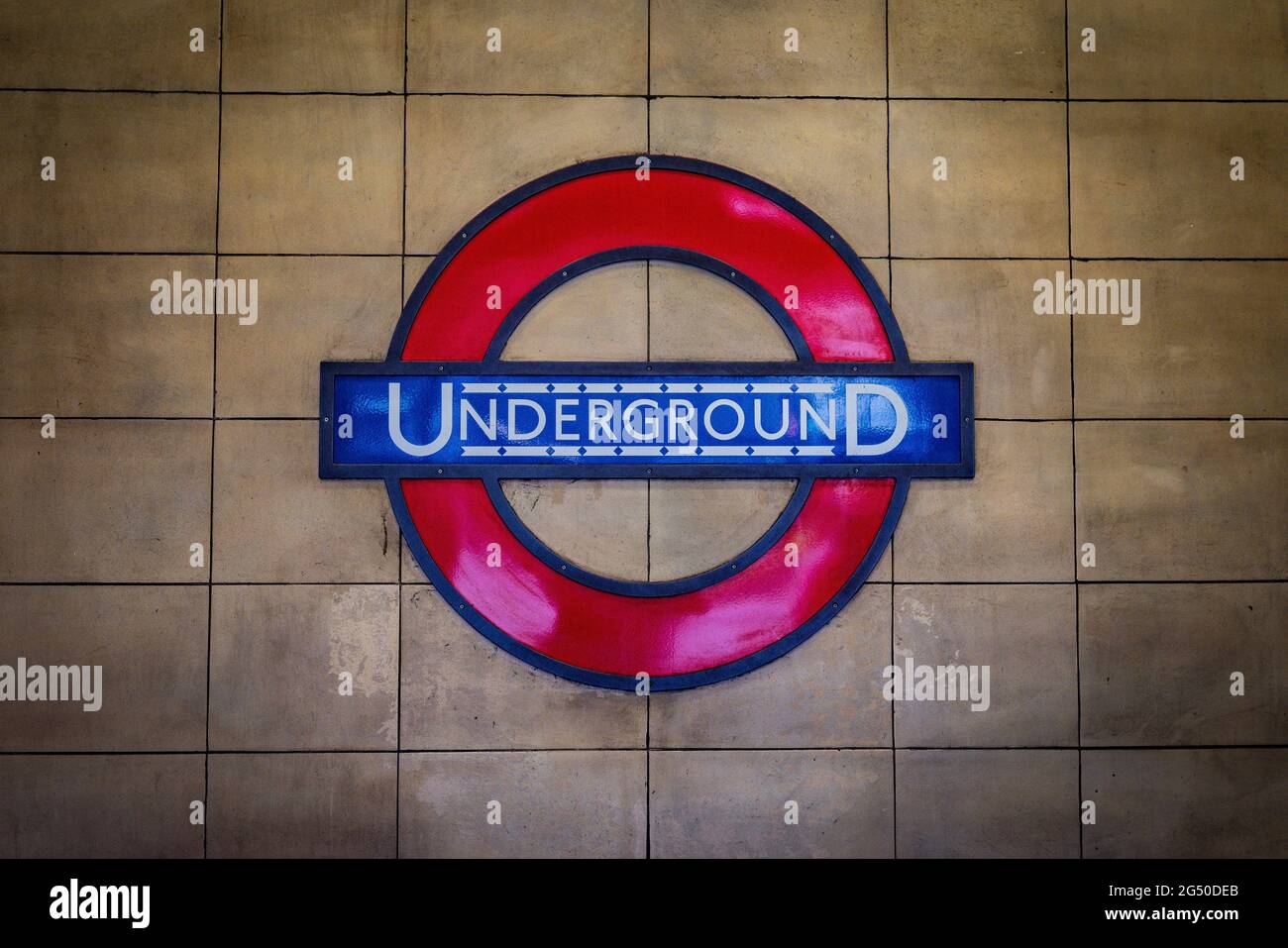 Un cartello su un pavimento piastrellato con la metropolitana di Londra sullo sfondo Foto Stock