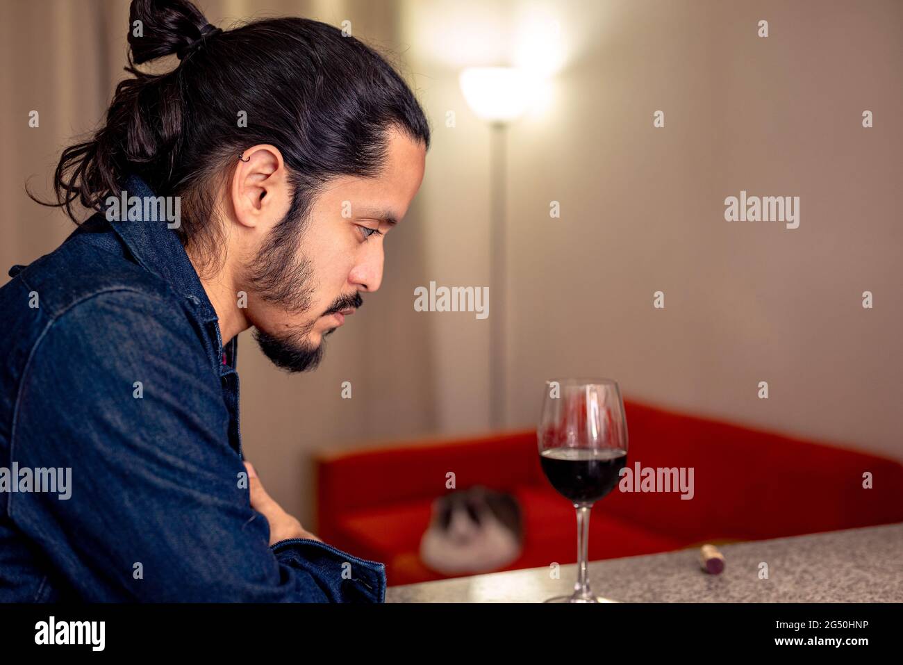 Giovane latino depresso bevendo vino rosso a casa in soggiorno Foto Stock