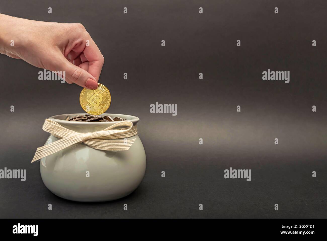 Investimenti, accumulo di criptovaluta. Bitcoin in mano, la mano femminile mette una moneta di bitcoin oro in una pentola di monete. Denaro digitale, posto per il testo Foto Stock