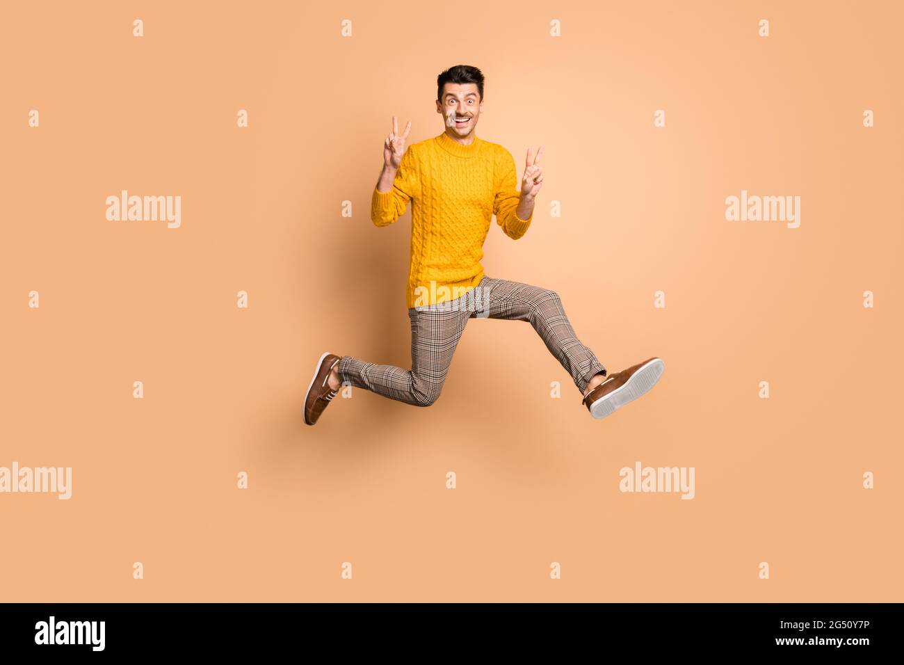 Ritratto fotografico a lunghezza intera di un uomo divertente che fa saltare due segni a V su isolato su sfondo color beige pastello Foto Stock