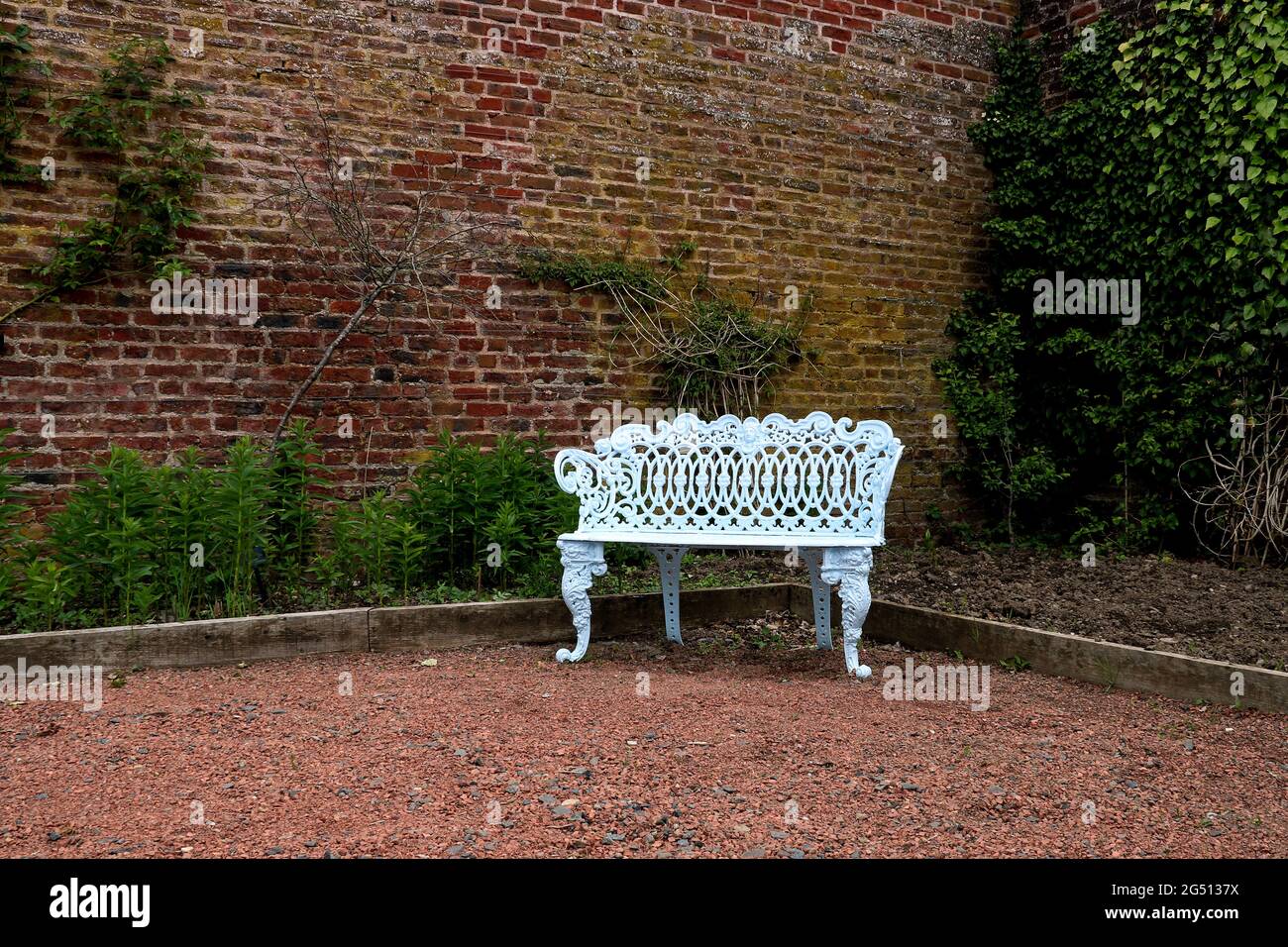 Panca in metallo bianco in un angolo di un giardino di casa di campagna  Foto stock - Alamy