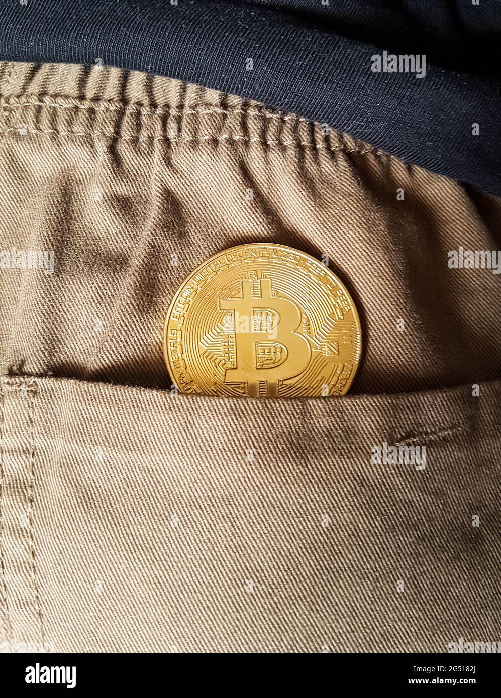 Moneta d'oro Bitcoin in una tasca posteriore di jeans Foto Stock