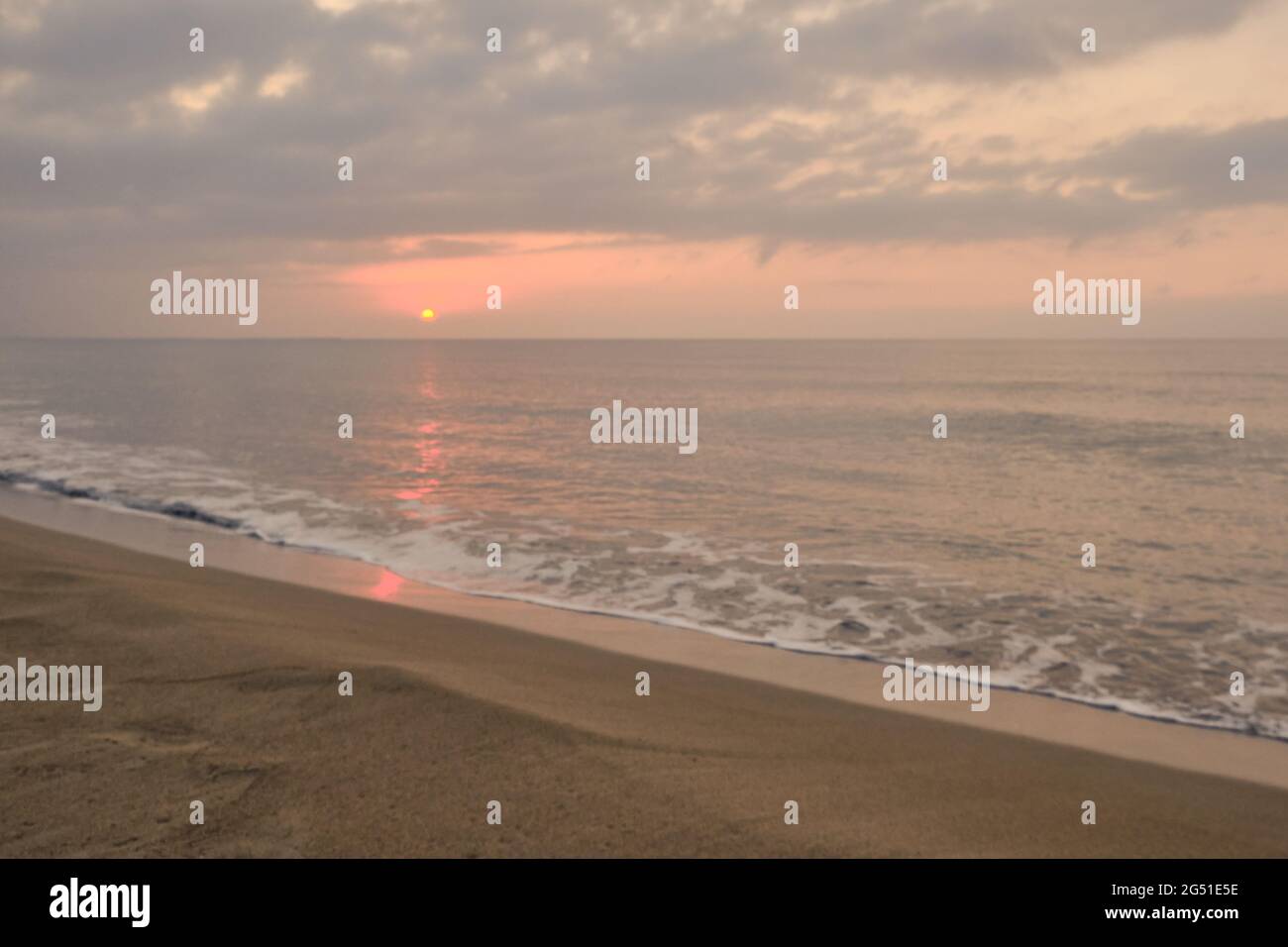 Alba nuvolosa sulla spiaggia di sabbia deserta Foto Stock