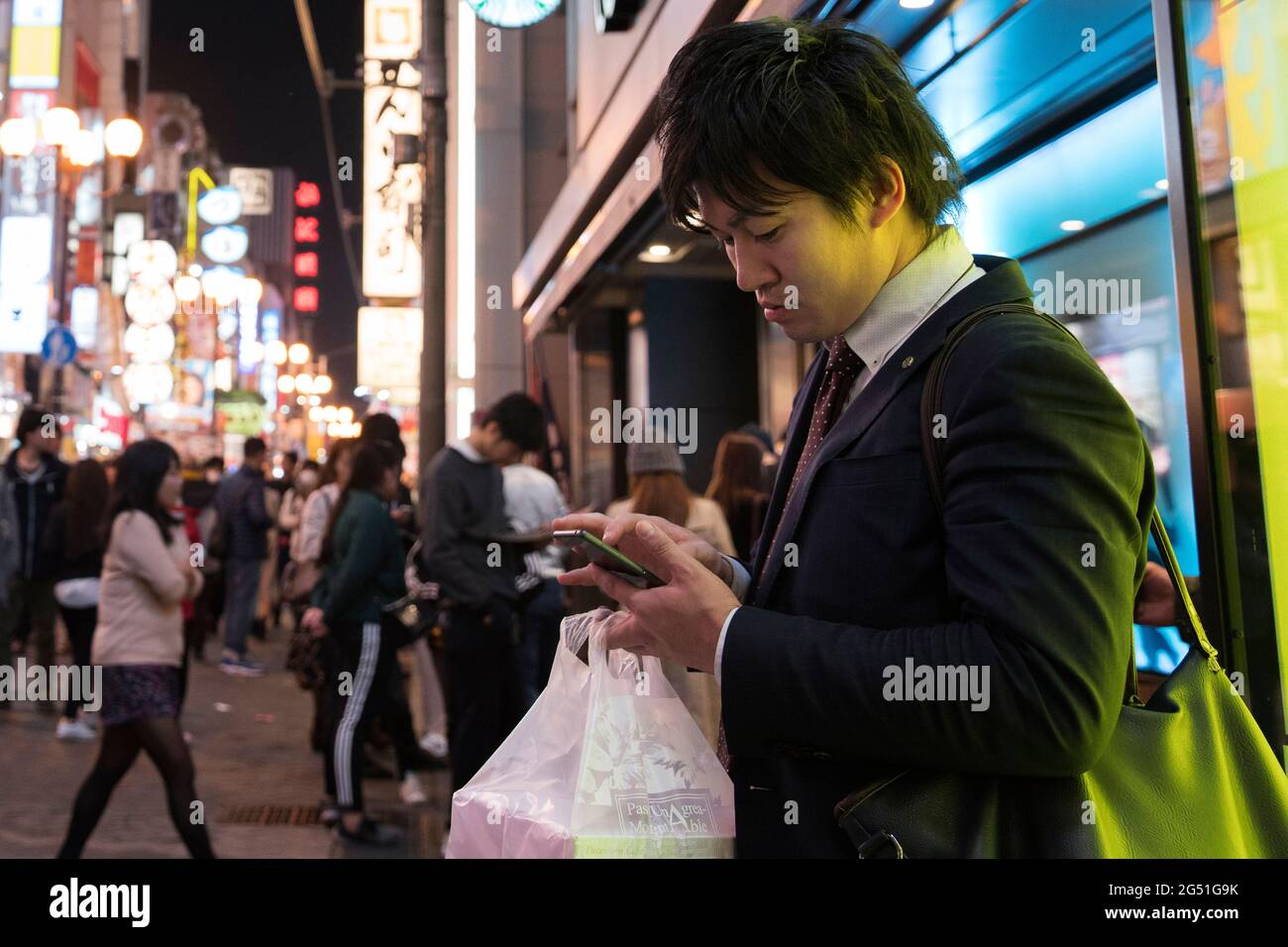 Un uomo sul suo cellulare a Osaka, Giappone Foto Stock