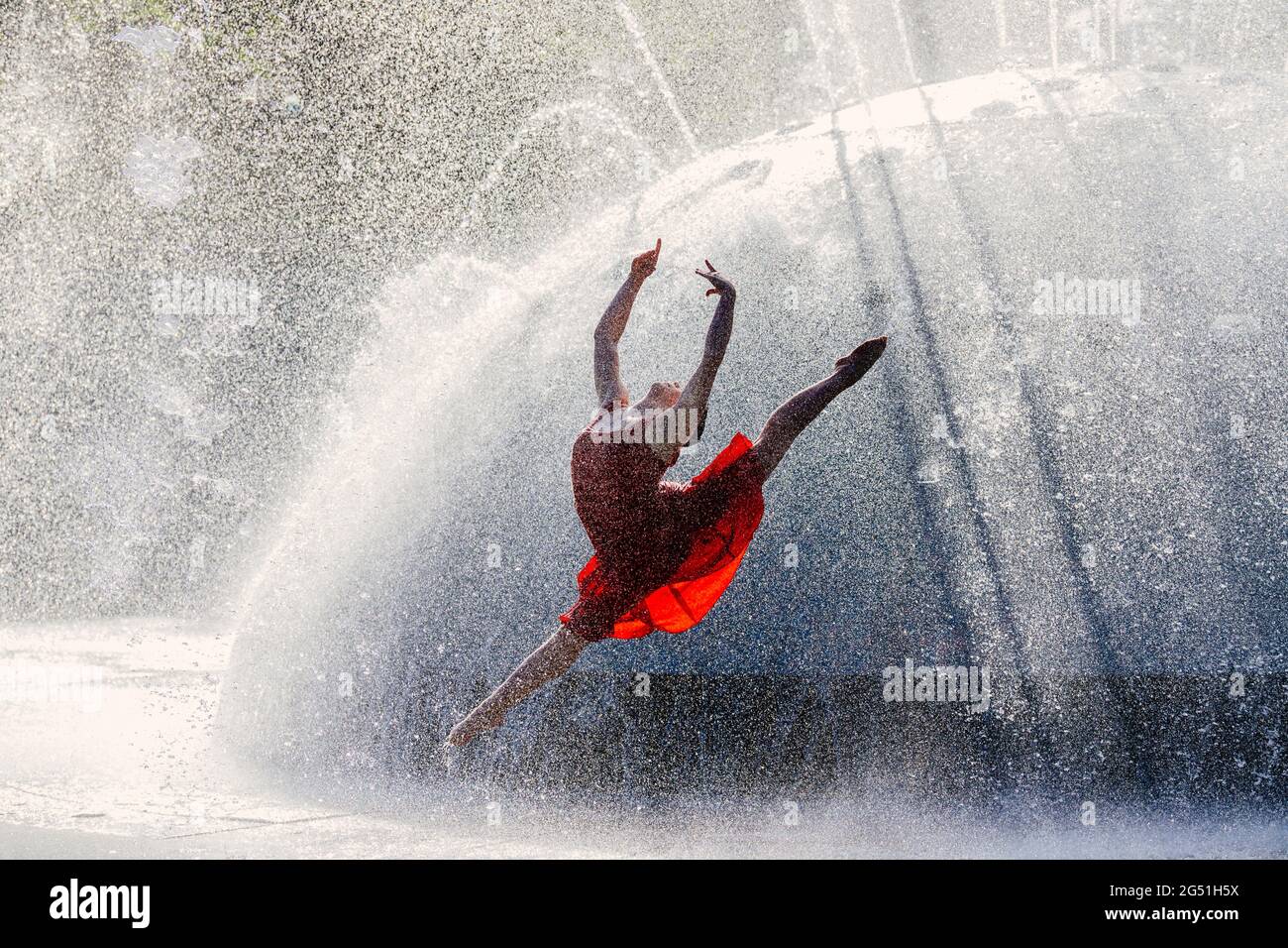 Donna in abito rosso che balla contro la fontana Foto Stock