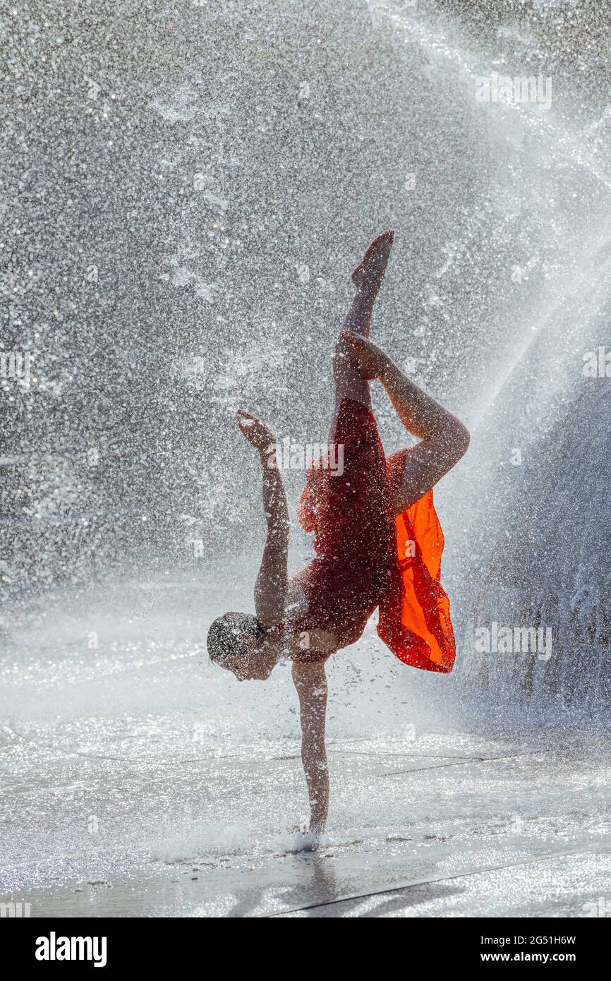 Donna in abito rosso che balla contro la fontana Foto Stock