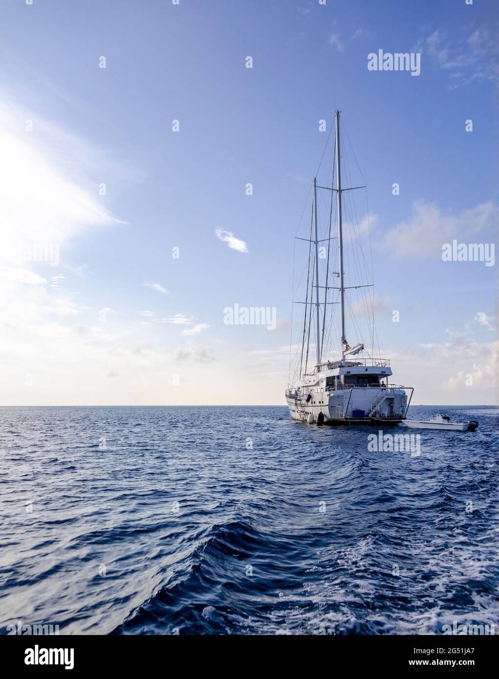 Una barca a vela e un motoscafo nel mezzo del mare ondulato in una giornata di sole. Foto Stock