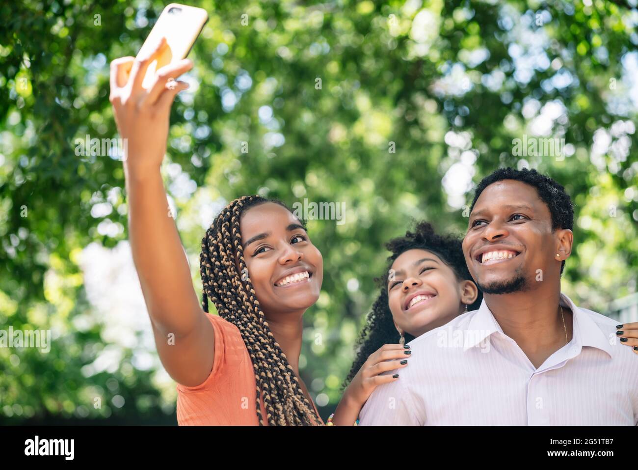 Famiglia che prende un selfie con un telefono cellulare al parco. Foto Stock