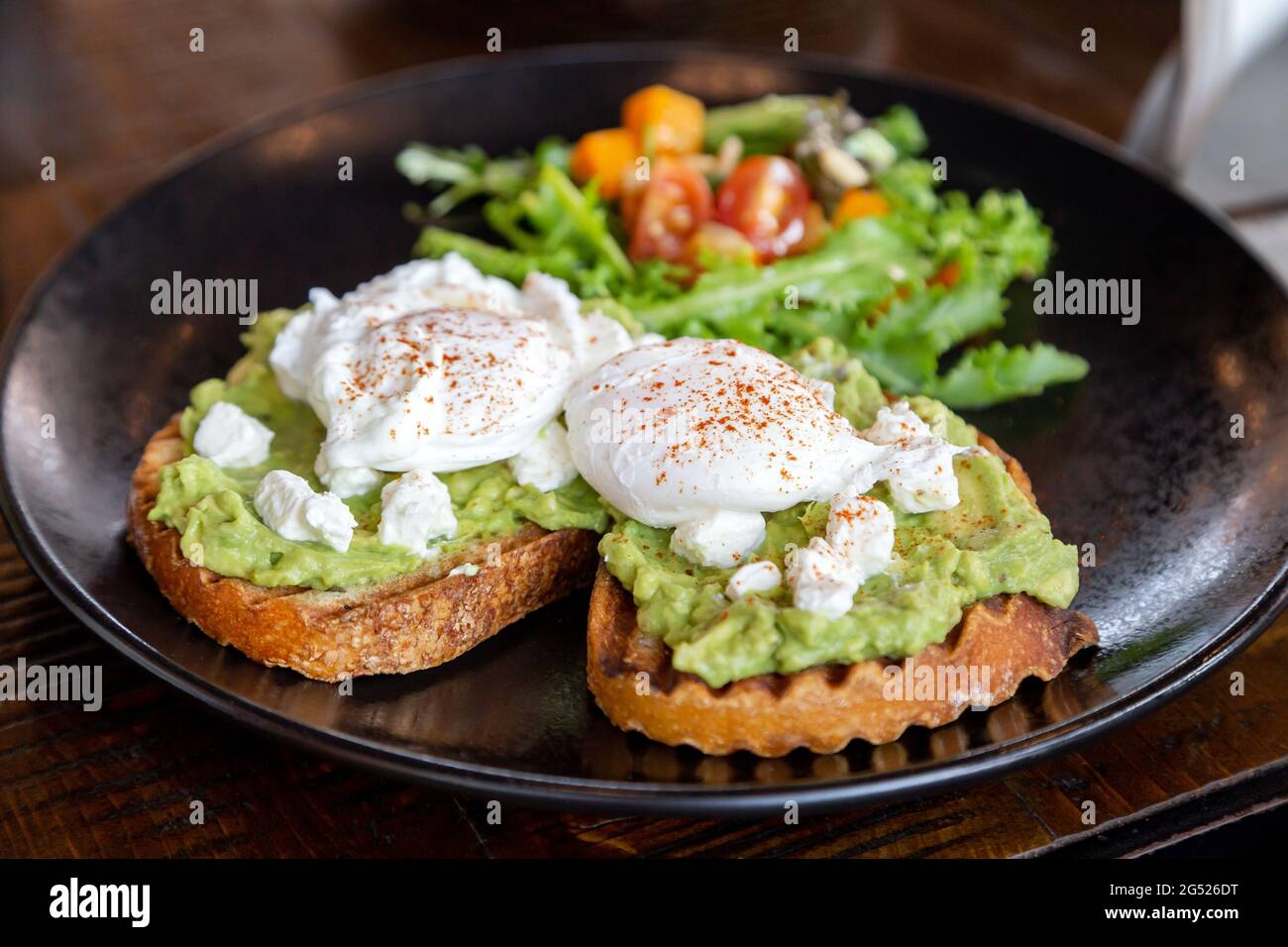 Due toast di avocado con uova in camicia e insalata fresca sul lato, sana e deliziosa colazione Foto Stock
