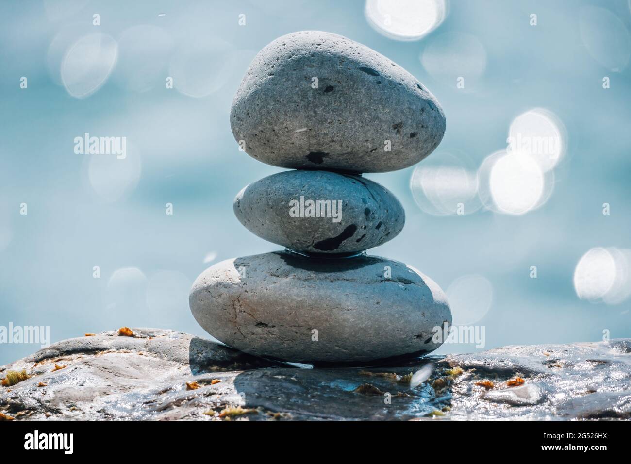Equilibrata piramide di ciottoli sulla spiaggia in una giornata di sole. Abstract Sea bokeh sullo sfondo. Messa a fuoco selettiva. Pietre Zen sulla spiaggia di mare, meditazione Foto Stock