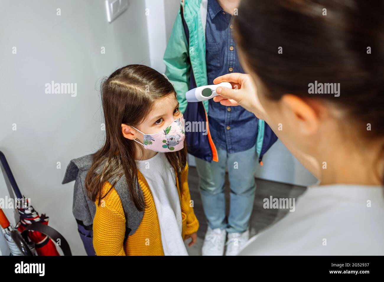 Madre che controlla la temperatura di sua figlia prima di andare a scuola Foto Stock