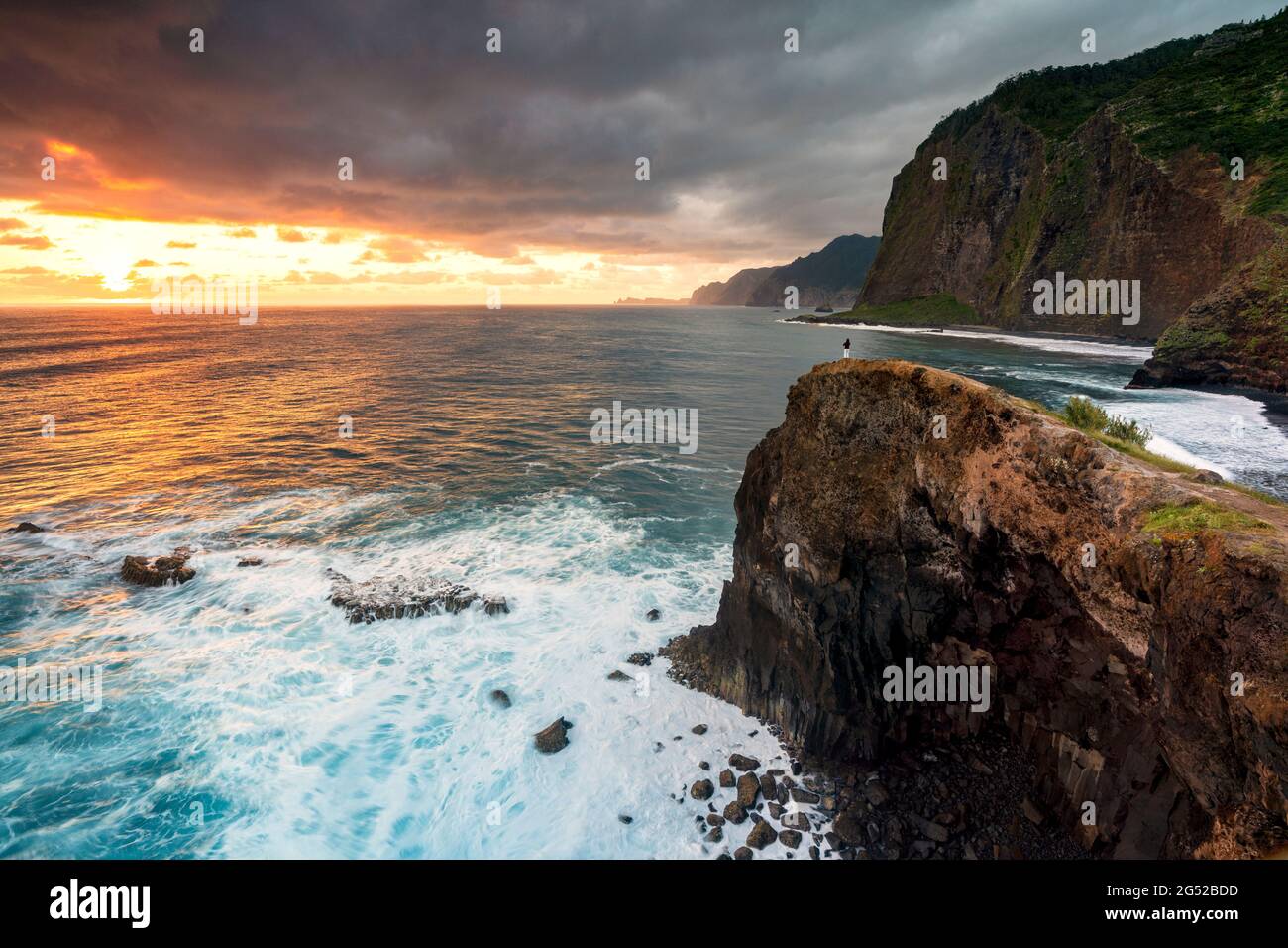 Un uomo che ammira l'alba sull'oceano dalla cima della scogliera, l'isola di Madeira, Portogallo Foto Stock