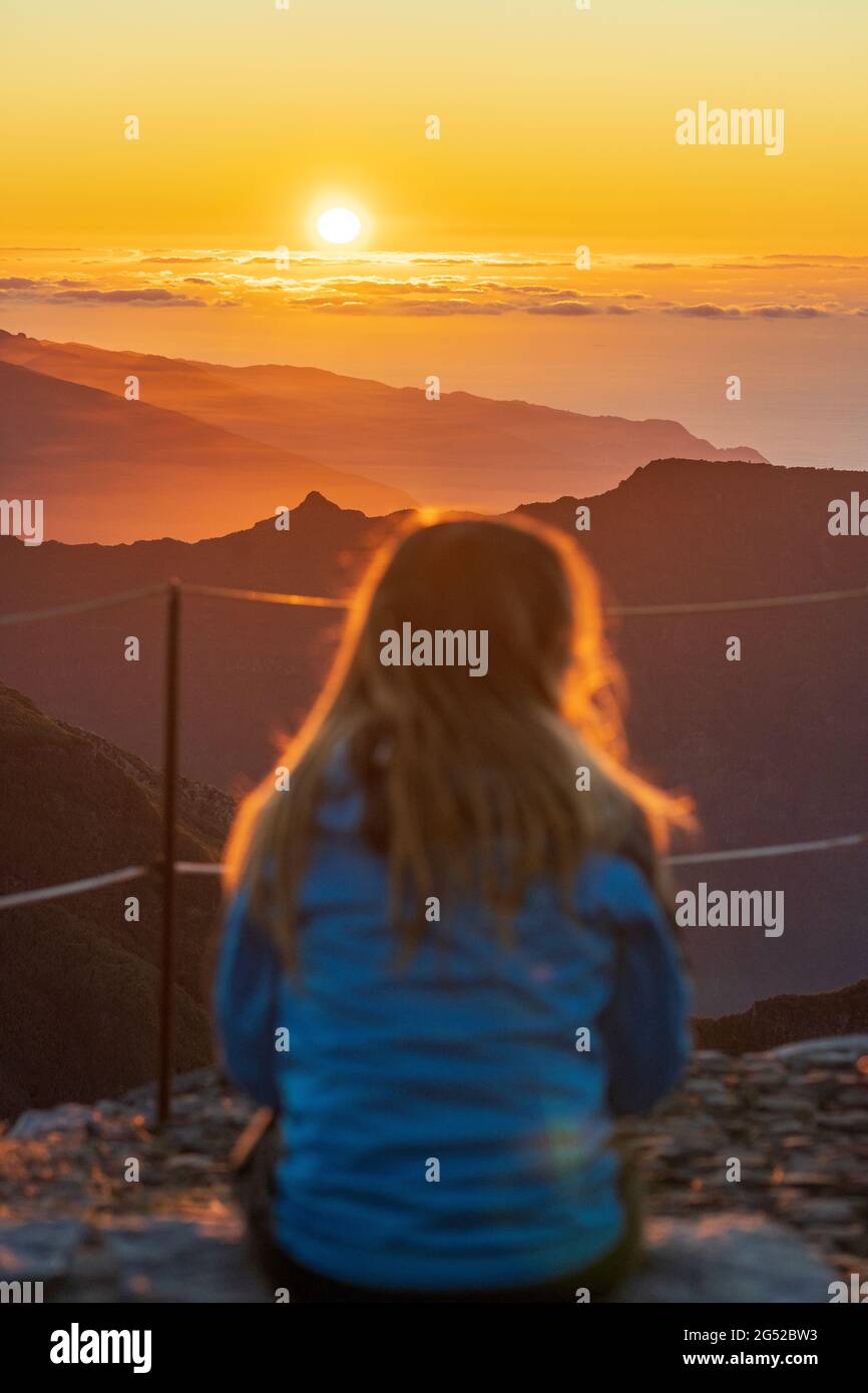 Giovane donna che ammira le montagne al tramonto dalla vetta di Pico Ruivo, Madeira, Portogallo Foto Stock