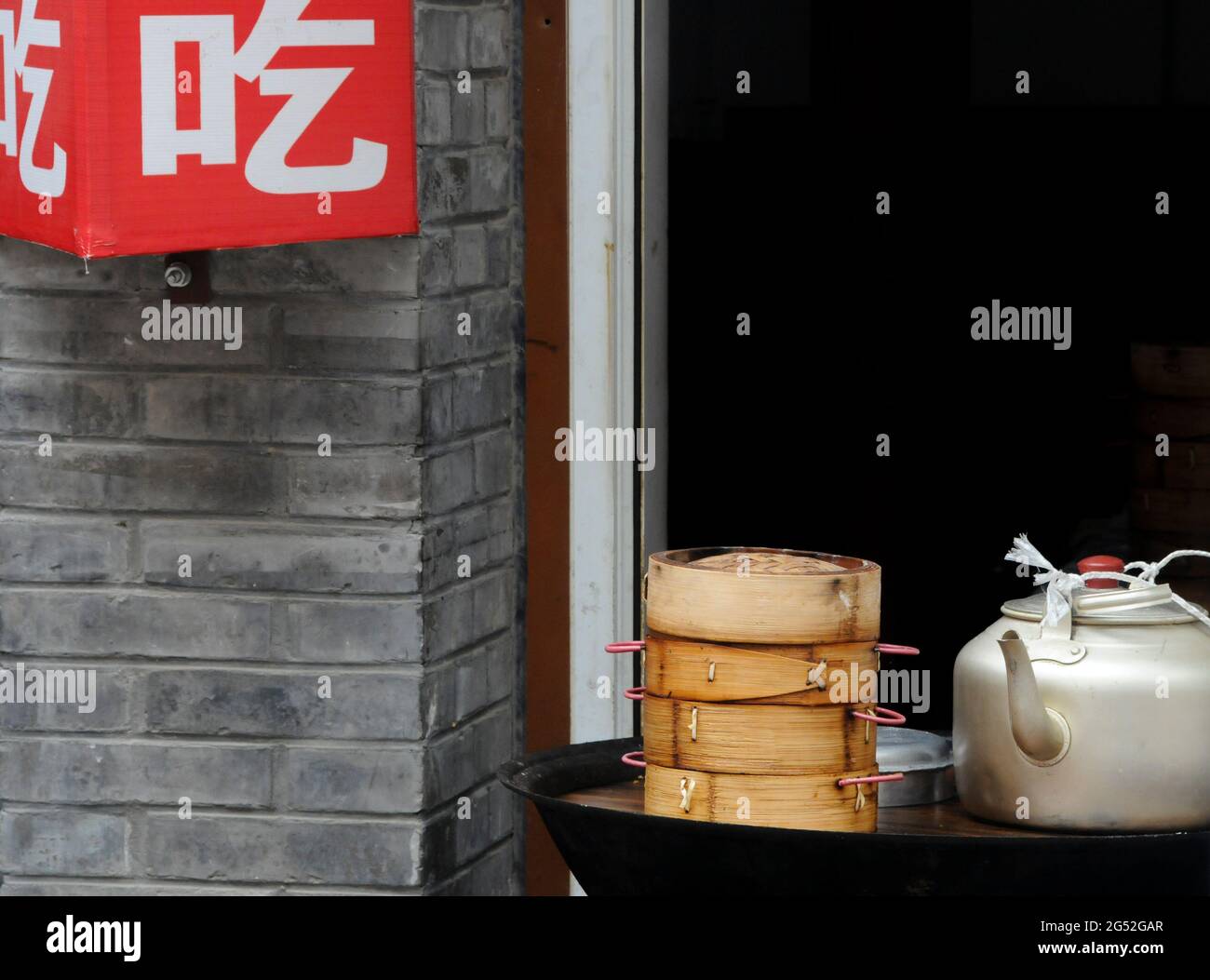 Cesto cinese di bambù vaporiera e vecchio bollitore d'acqua fuori di un ristorante cinese. Pechino, Cina. Foto Stock
