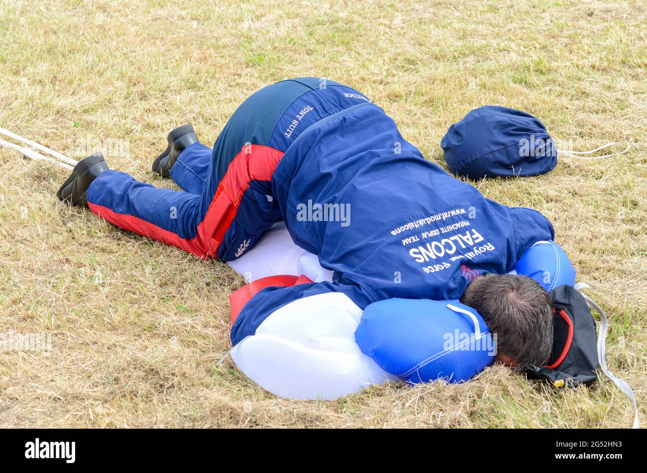 Paracadutista del team di visualizzazione paracadute Royal Air Force Falcons spinge comicamente il suo corpo in un paracadute per comprimerlo dopo l'atterraggio Foto Stock