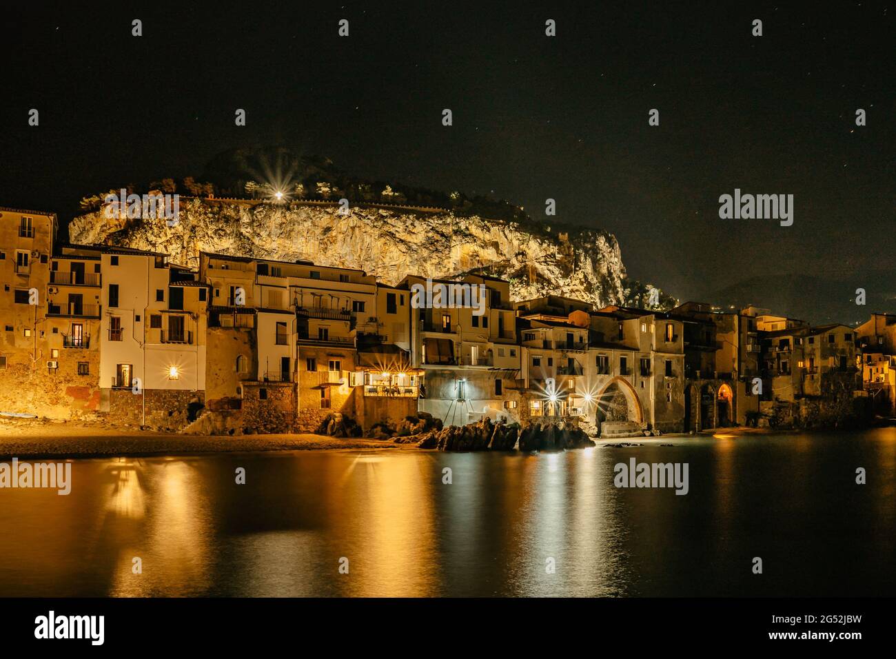 Vista notturna della spiaggia di Cefalu, Sicilia, Italia, centro storico illuminato con colorate case sul lungomare, mare e la Rocca Cliff.attraente paesaggio estivo Foto Stock
