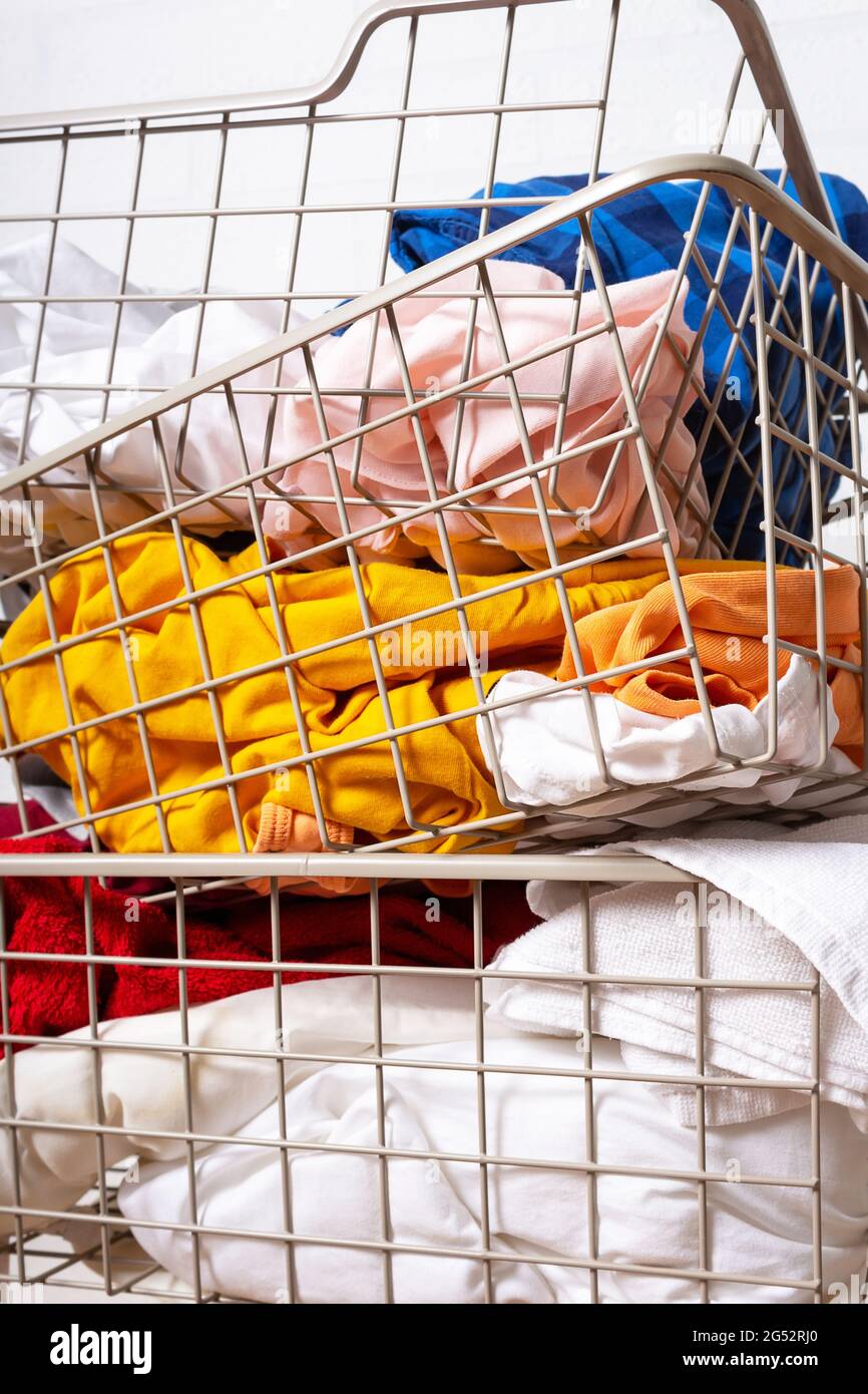 Pile di bucato sporco e colorato in cestini. Foto Stock