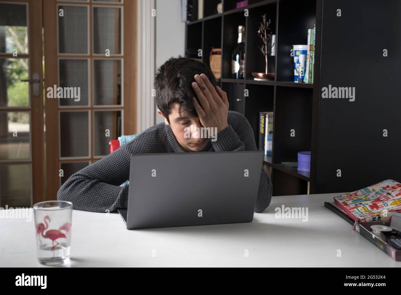 Stanco studente britannico, età 13-14 anni, avendo lezioni online durante la pandemia di Covid-19, Surrey, Regno Unito Foto Stock