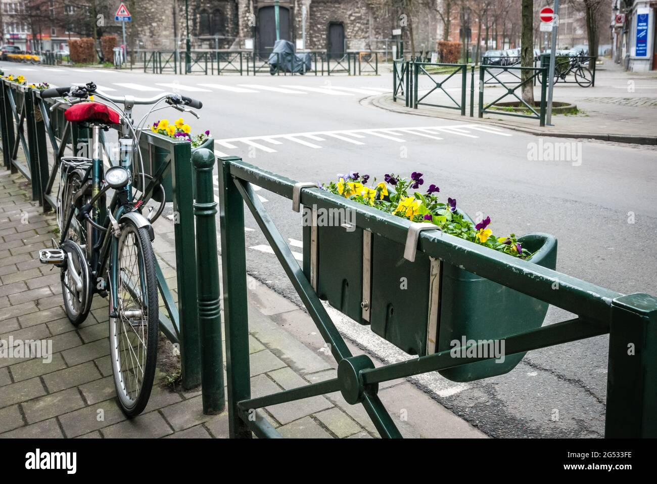La sola bicicletta parcheggiata vicino alla recinzione infatuata con fiori Foto Stock