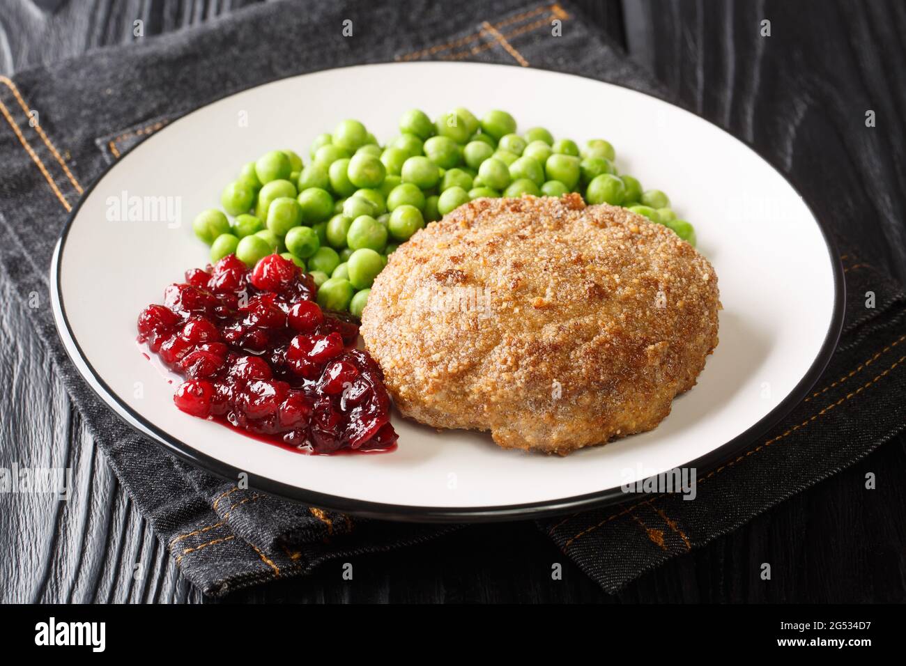 Delizioso polpette di vitello con contorno di piselli verdi e marmellata di lingonberry primo piano in un piatto sul tavolo. Orizzontale Foto Stock