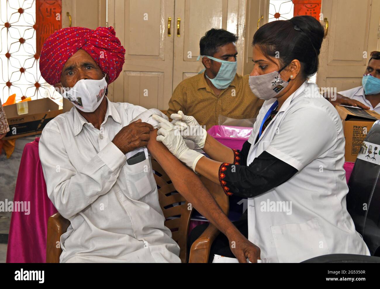 Beawar, Rajasthan, India, 24 giugno 2021: Un medico somministra una dose di Covisield (vaccino COVID-19) ad un uomo rurale durante una mega vaccinazione in un centro di vaccinazione a Beawar. Variante Delta Plus di Coronavirus rilevata in circa 80 paesi tra cui India, Stati Uniti, Regno Unito, Portogallo, Giappone, Nepal, Polonia, Cina e Russia. Nonostante l’interruzione di tutte le esportazioni in aprile e il beneficio di un’enorme industria produttrice di vaccini, l’India ha coperto solo il 4% della sua vasta popolazione, mettendola molto indietro rispetto alla maggior parte dell’Occidente e della Cina, che sta distribuendo circa 20 milioni di dosi al giorno. Credit: Sumit Saraswat/Alamy Live News Foto Stock