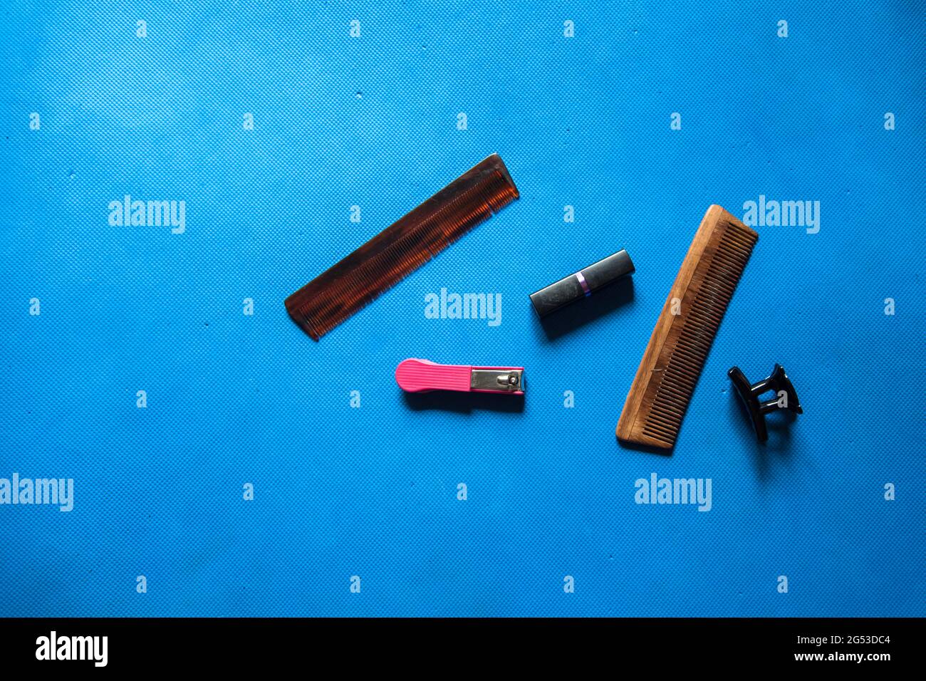 Accessori per la cura del corpo: Regolacapelli, pettine, clip per capelli e rossetto su sfondo con messa a fuoco selettiva Foto Stock