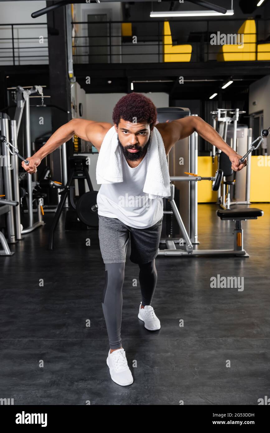 uomo afro-americano sopportato che si esercita sulla macchina di addestramento di estensione del braccio Foto Stock