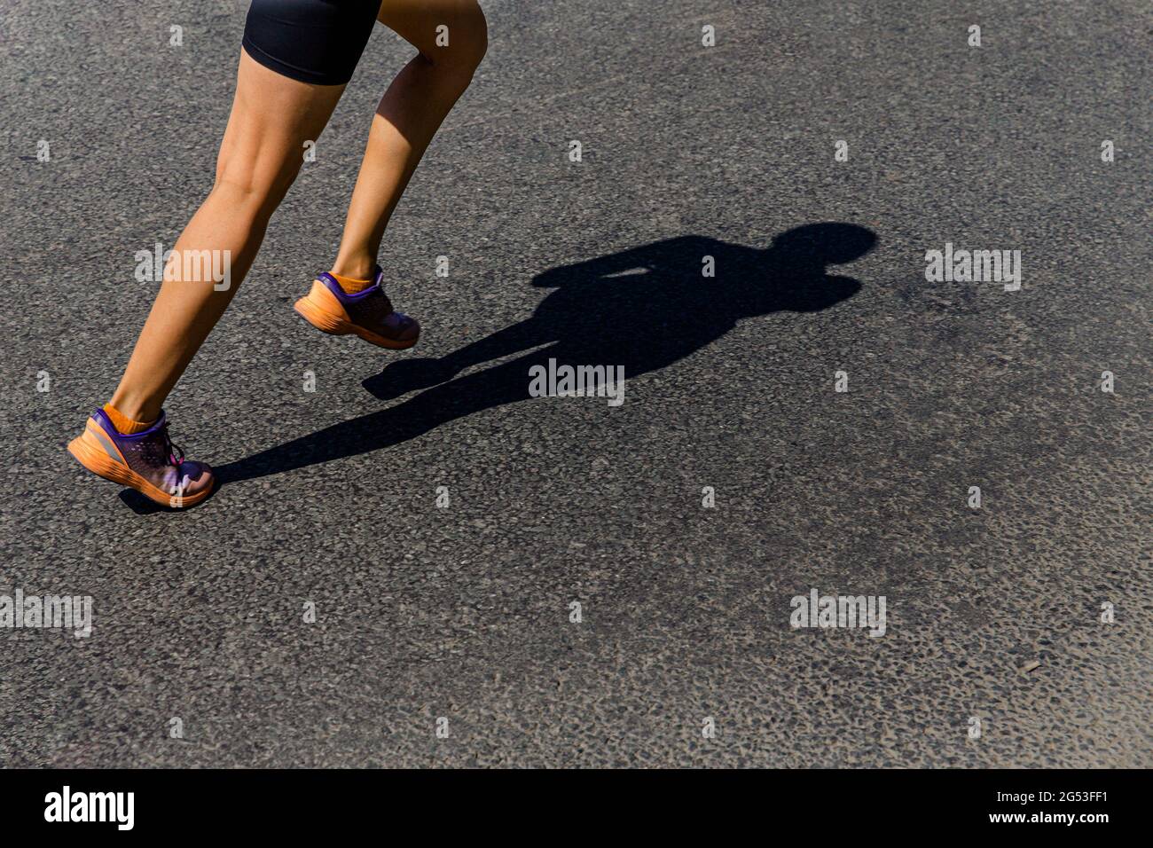 ragazza runner correre ombra su strada buia Foto Stock