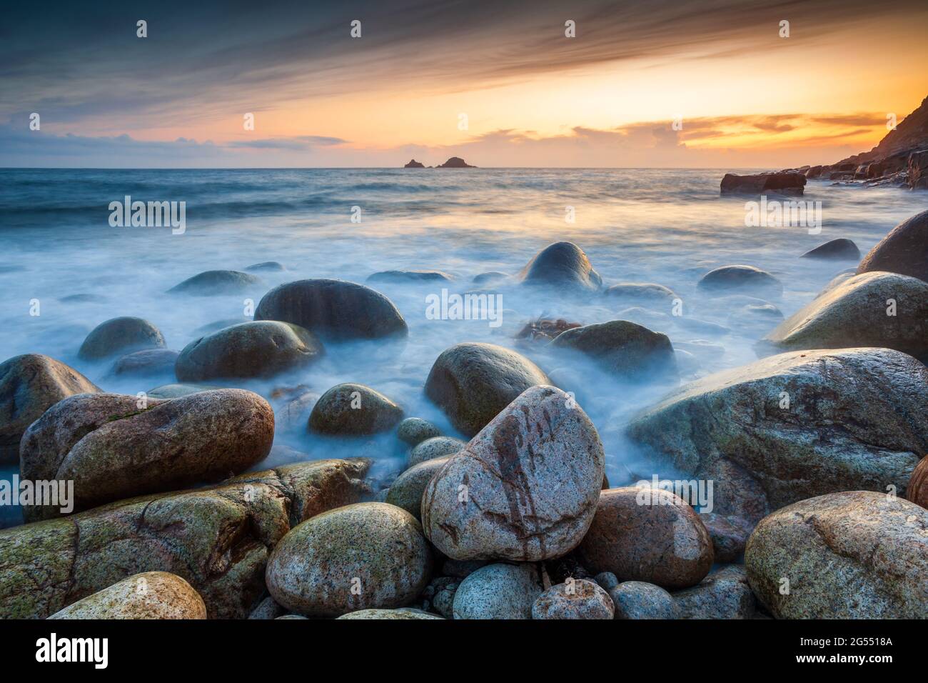 Tramonto a Porth Nanven in Cornovaglia, con i Brison Rocks in lontananza. Foto Stock