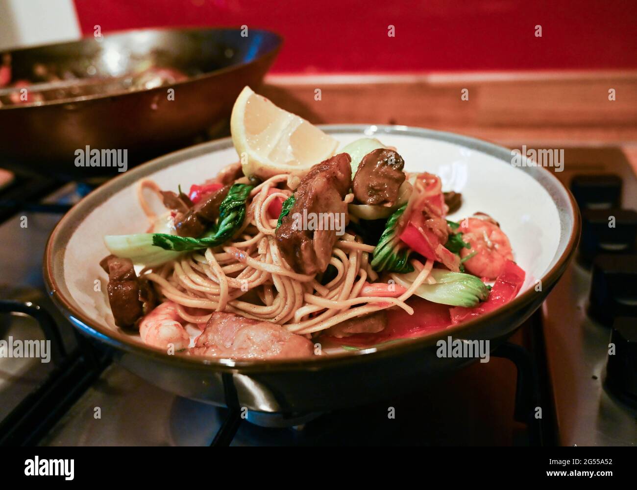 Cucina casalinga mescolare fritto Singapore Noodles con maiale, gamberi e uova noodle Foto Stock