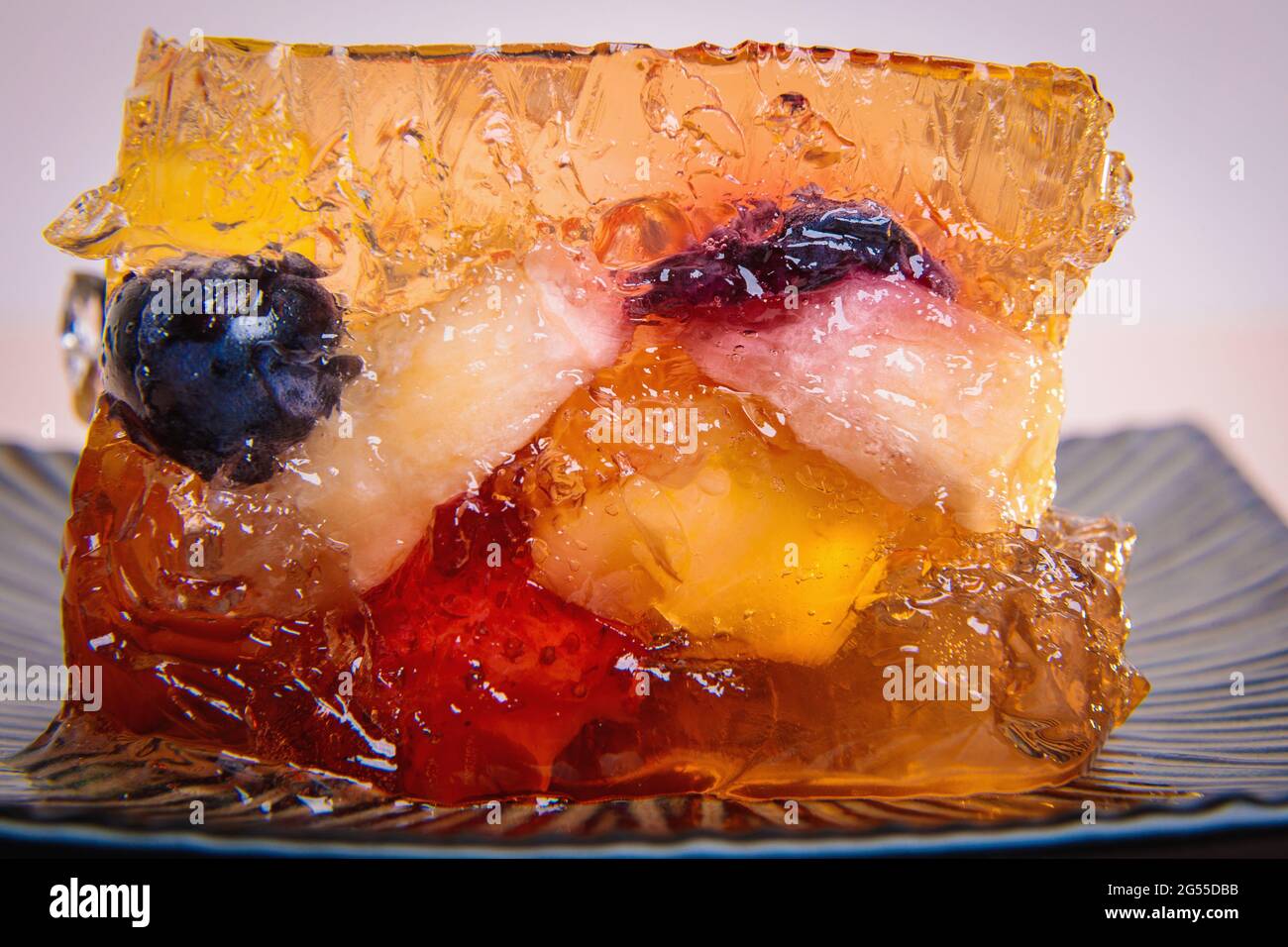 Gelatina di frutta e bacche diverse su un piatto quadrato. Dessert. Primo piano Foto Stock
