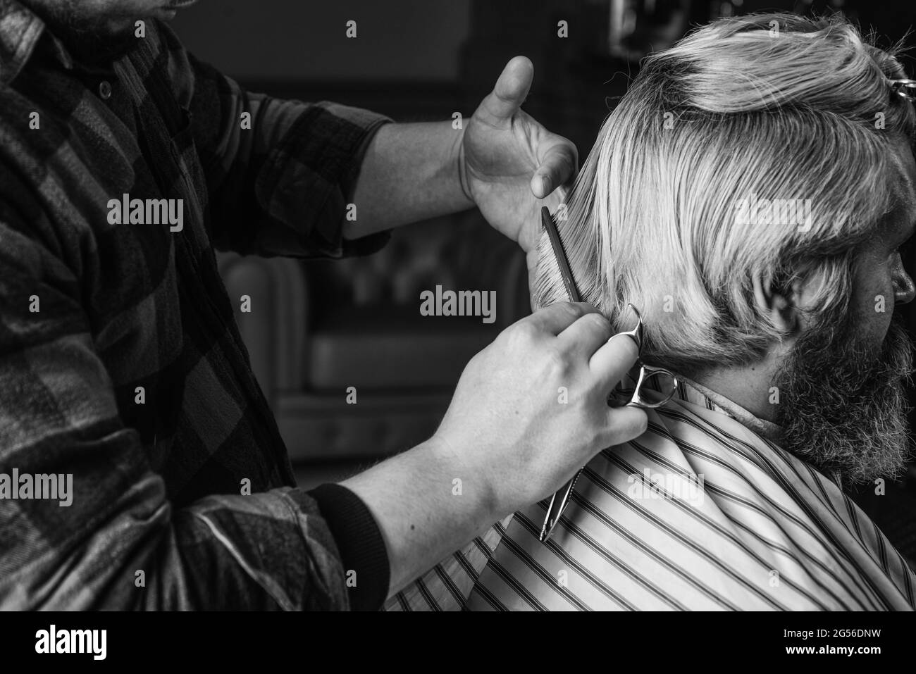 Tagliare i capelli. Barbiere che fa acconciatura per uomo barbershop sfondo bearded. Ragazzo con lunghi capelli biondi tinti ravvicinato vista posteriore. Client hipster ottenere Foto Stock
