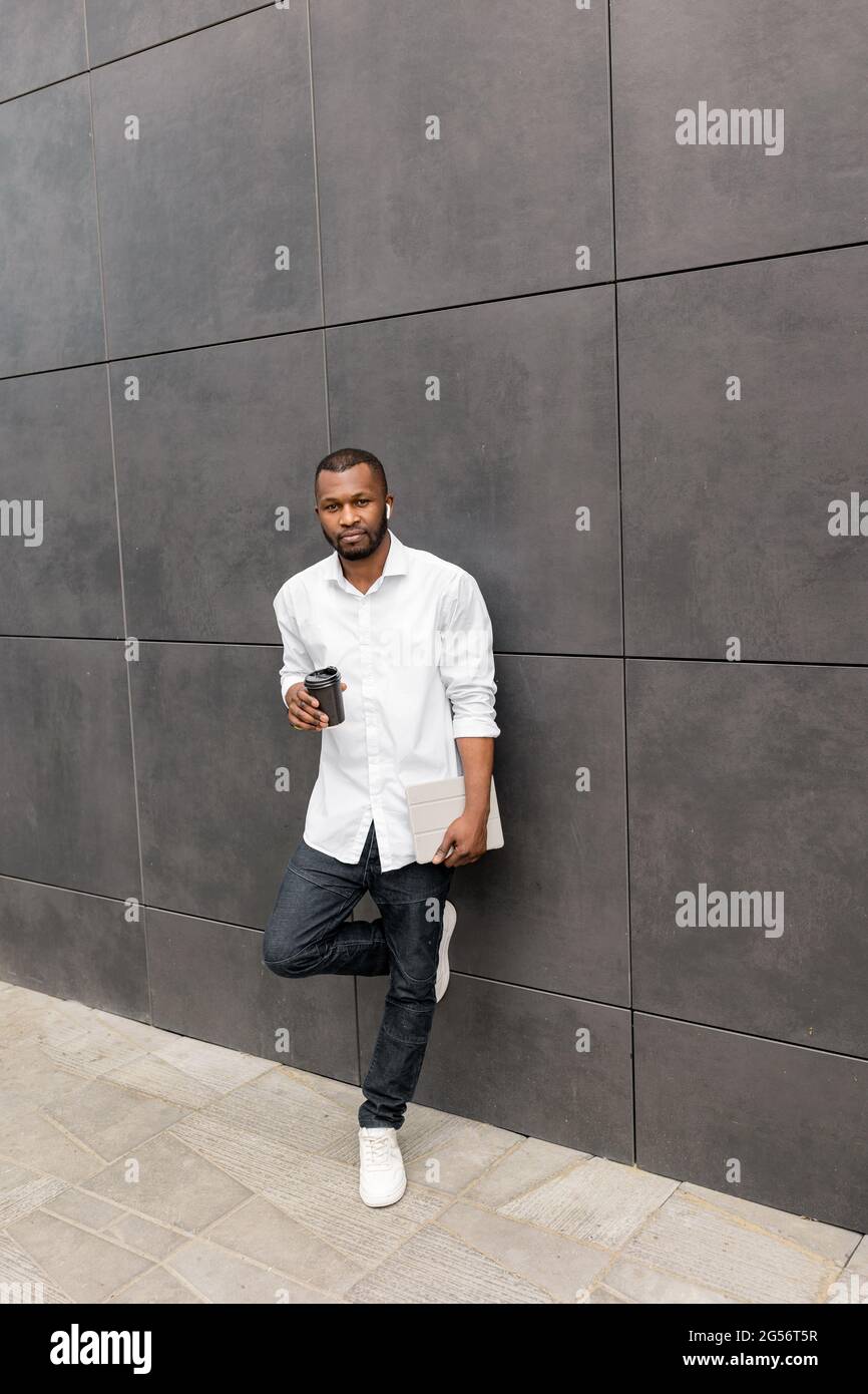 Elegante smiling afro American millennial freelance o studente in abiti casual dopo una pausa dopo giornata difficile, bere take away caffè Foto Stock