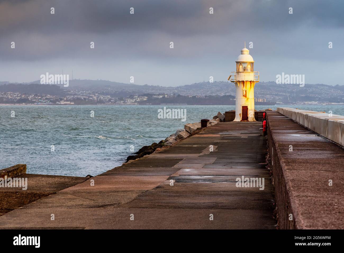 Il faro alla fine del frangiflutti all'entrata di Brixham Marina si affaccia Torbay nel Devon Sud. Preso subito dopo l'alba. Foto Stock