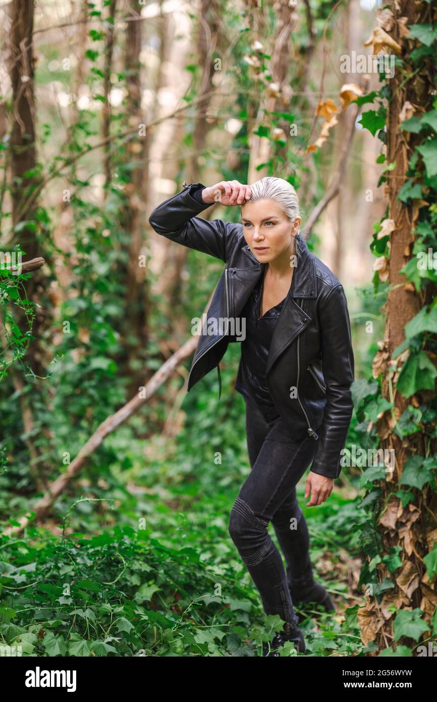 Moda in luoghi insoliti, giovane donna in giacca Edgy Moto nella foresta Foto Stock