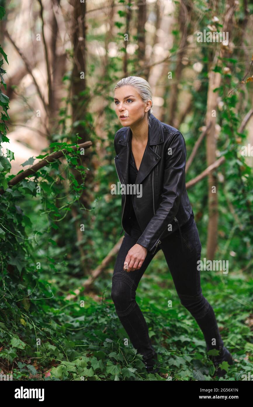 Moda in luoghi insoliti, giovane donna in giacca Edgy Moto nella foresta Foto Stock