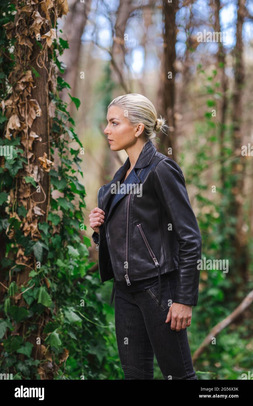 Moda in luoghi insoliti, giovane donna in giacca Edgy Moto nella foresta Foto Stock