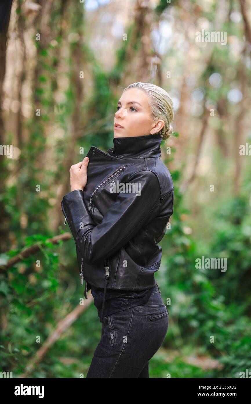 Moda in luoghi insoliti, giovane donna in giacca Edgy Moto nella foresta Foto Stock