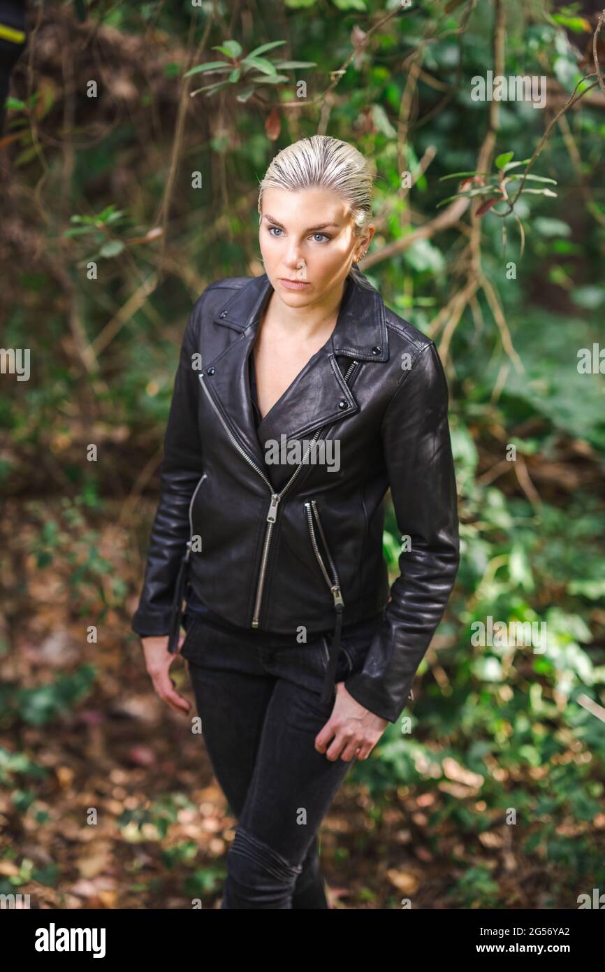 Moda in luoghi insoliti, giovane donna in giacca Edgy Moto nella foresta Foto Stock