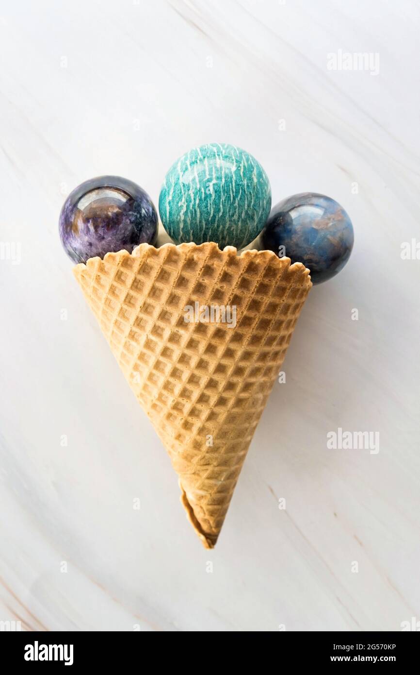 Primo piano di cono gelato con pietre di cristallo rotonde su sfondo di marmo come concetto di rinfresco o medicina alternativa di guarigione Foto Stock