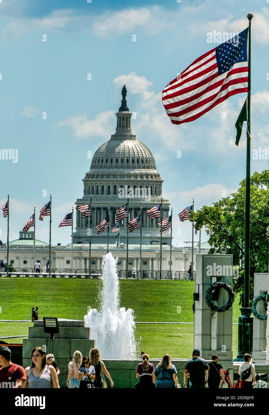 I visitatori si trovano di fronte alla fontana al Monumento commemorativo della seconda Guerra Mondiale a Washington D.C., con il Campidoglio sullo sfondo Foto Stock