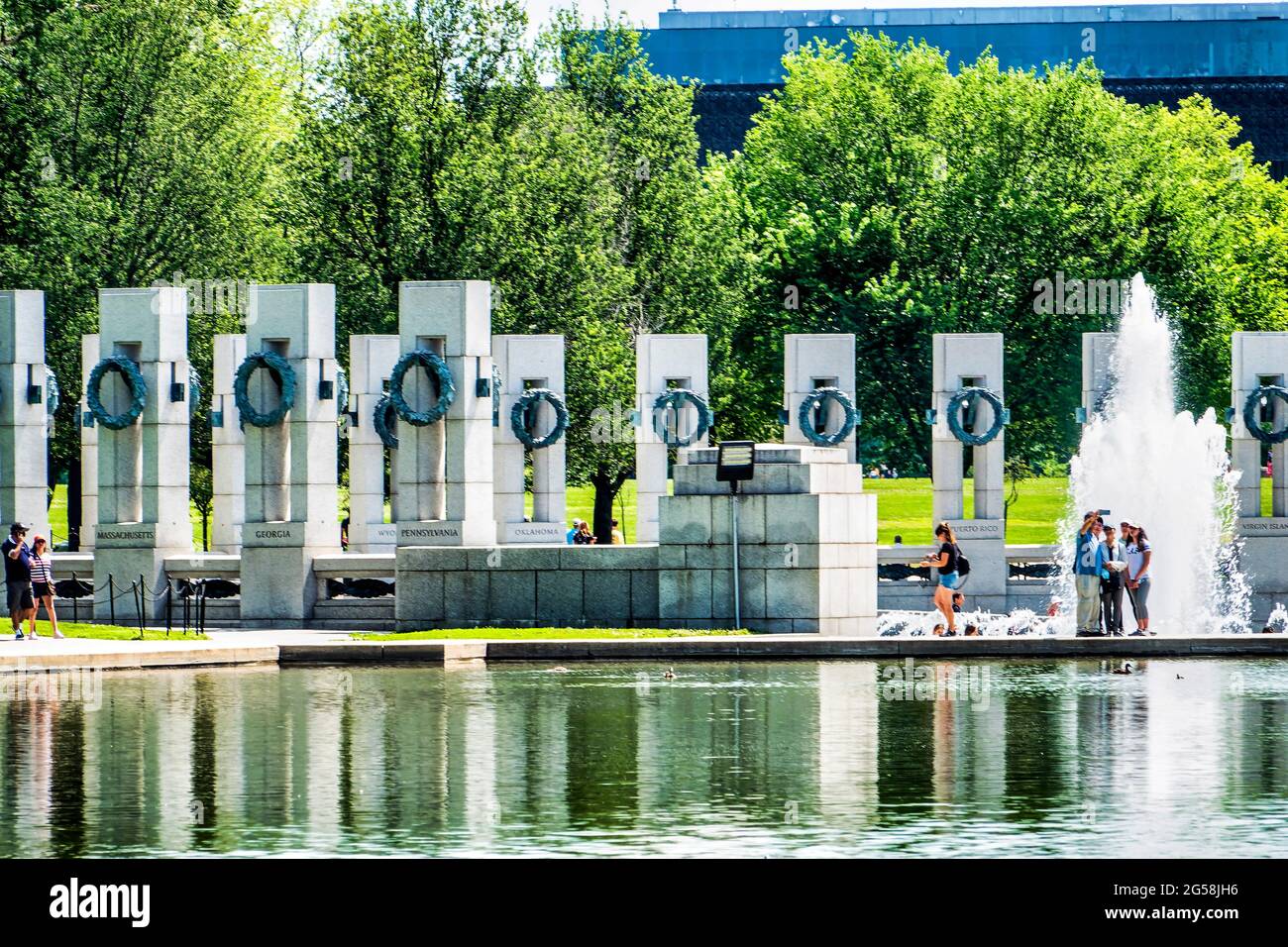 I visitatori si trovano di fronte alla fontana al Monumento commemorativo della seconda Guerra Mondiale a Washington D.C. Foto Stock