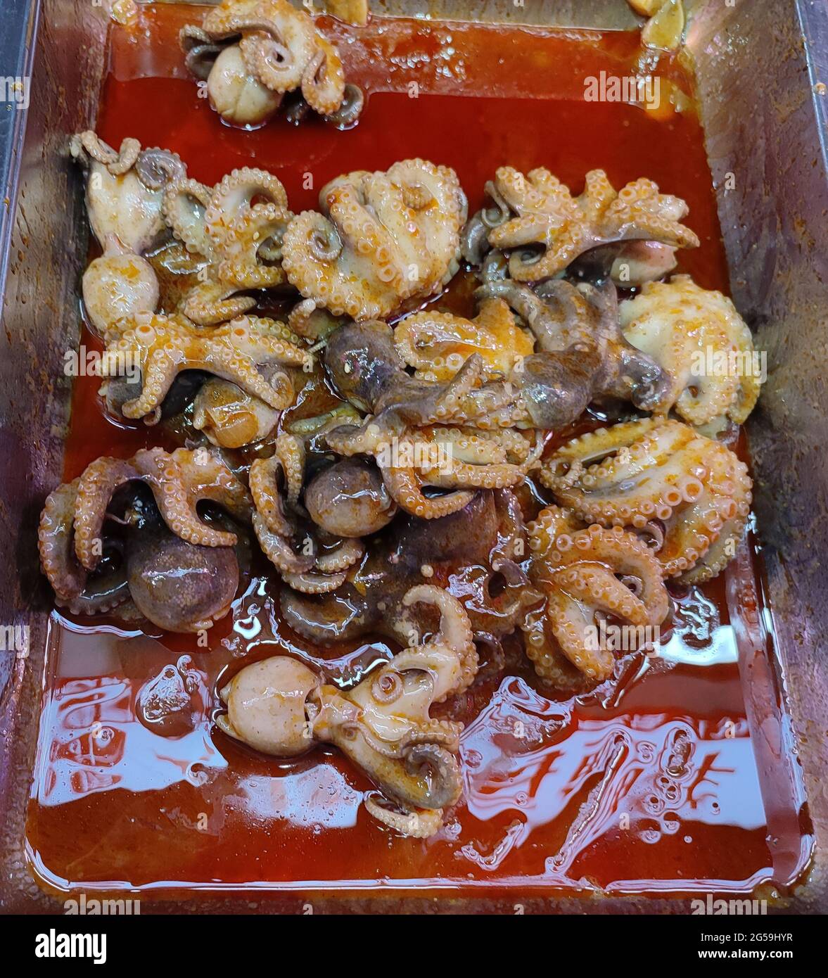 polpo brasato fresco nell'olio rosso per la vendita nel mercato notturno Foto Stock