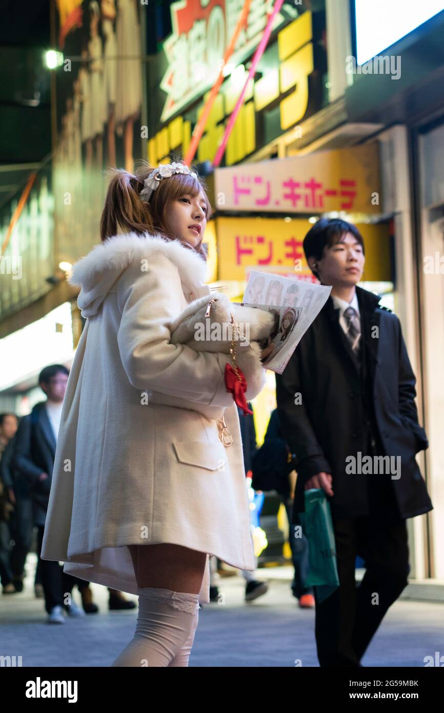Una ragazza in costume di una cameriera che consegna volantini per una cameriera per le strade di Akihabara a Tokyo, Giappone Foto Stock