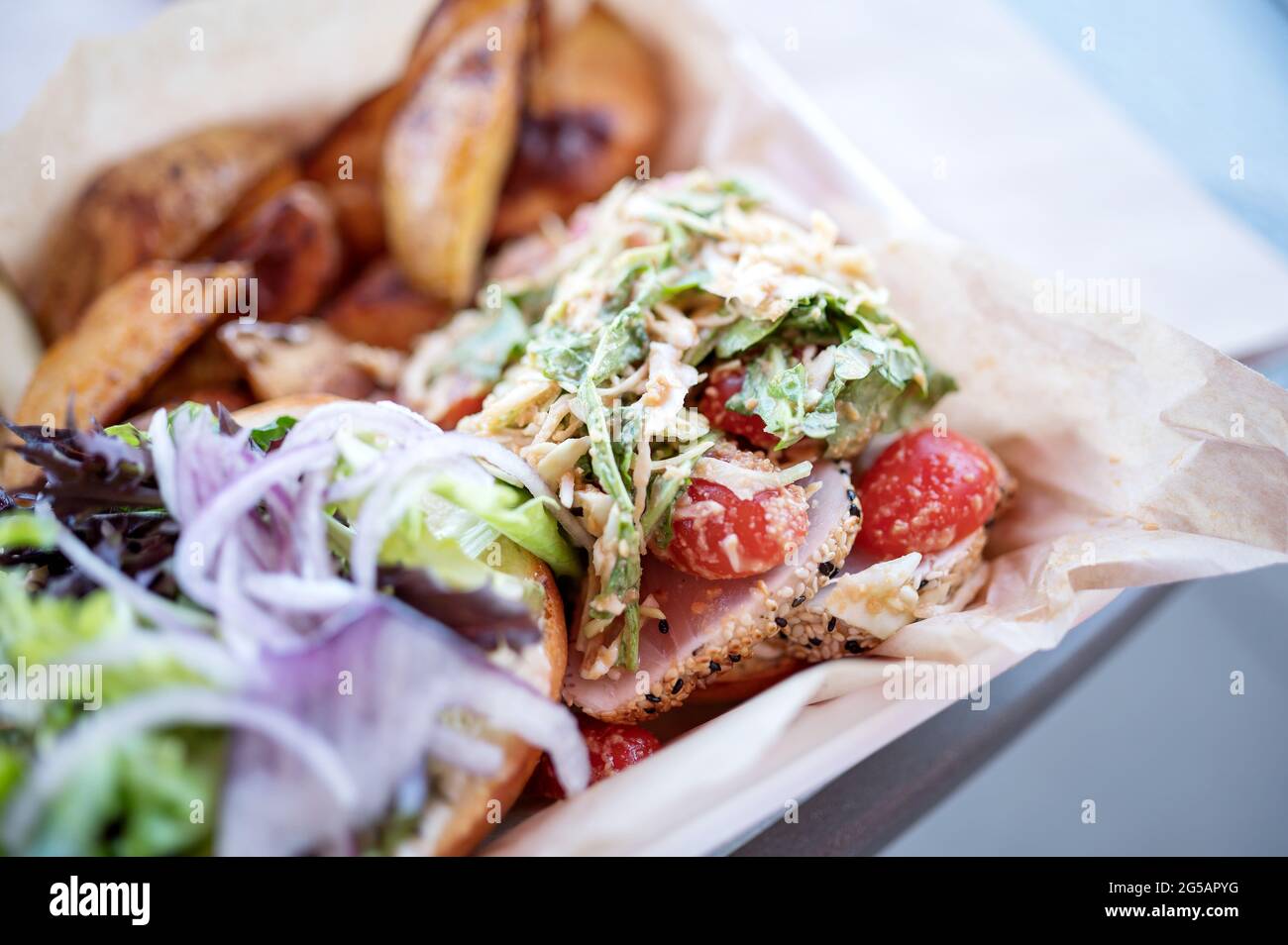Panino di tonno asiatico con pomodori e spicchi di patate. Foto Stock