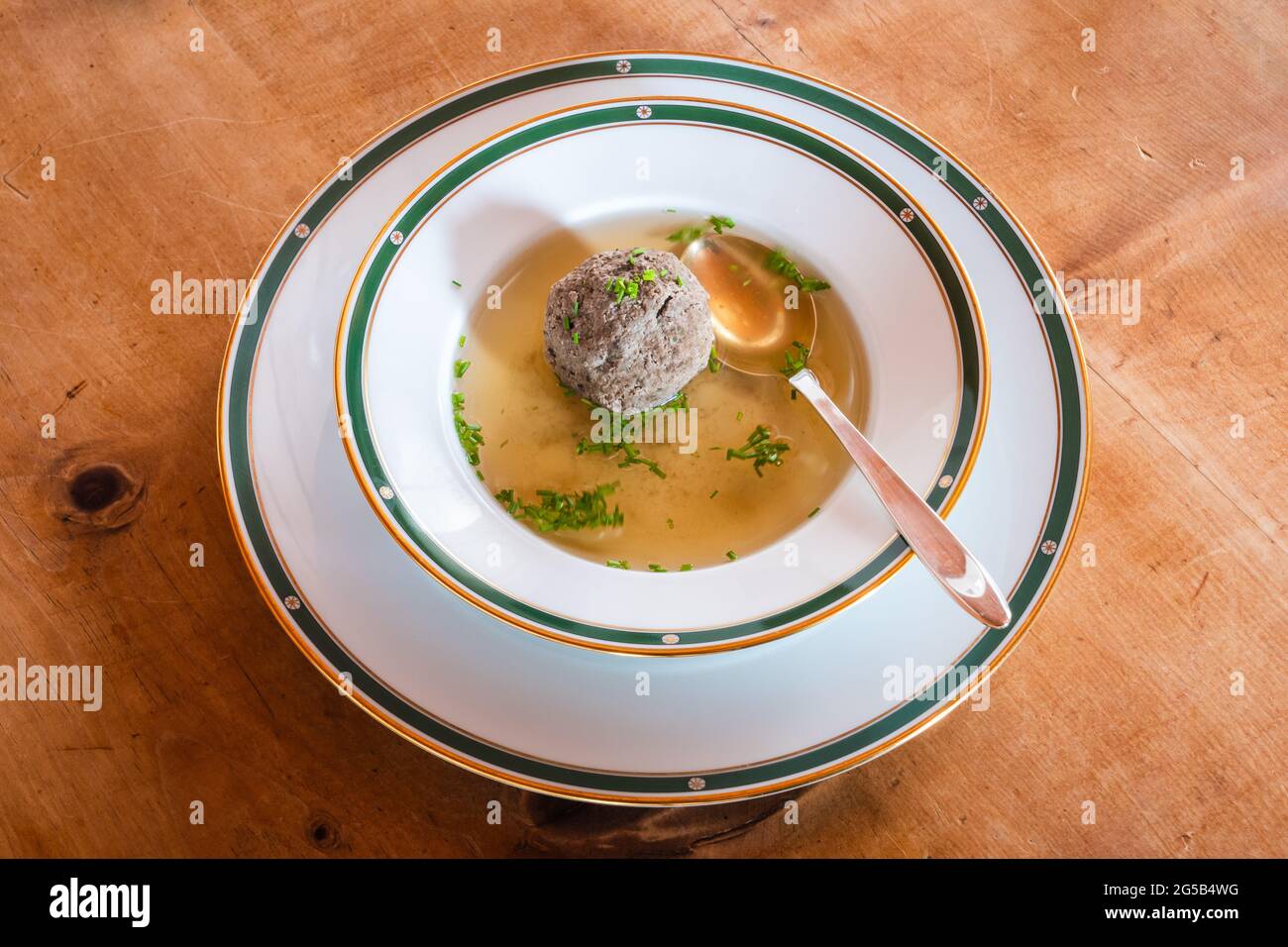 Leberknodelsuppe, una zuppa austriaca di fegato fittizio, una brodo di manzo con erba cipollina con cucchiaio Foto Stock