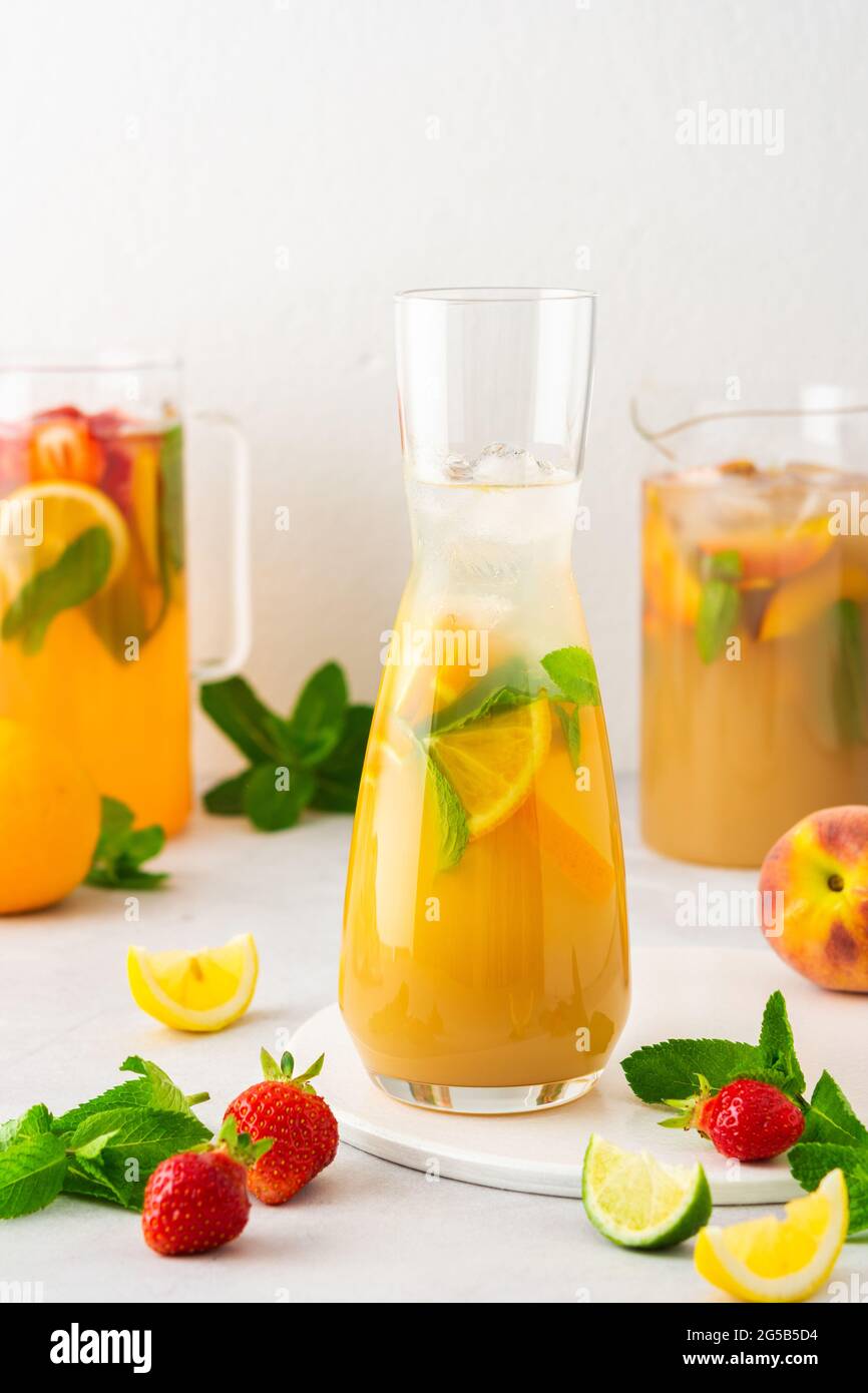 Brocche di fresche bevande alla frutta con spicchi di frutta, succhi estivi freddi con ghiaccio Foto Stock
