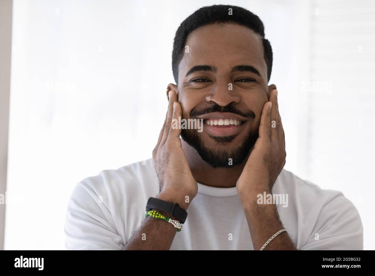 Felice razza mista uomo africano che tocca le morbide stoppie, barba elegante Foto Stock